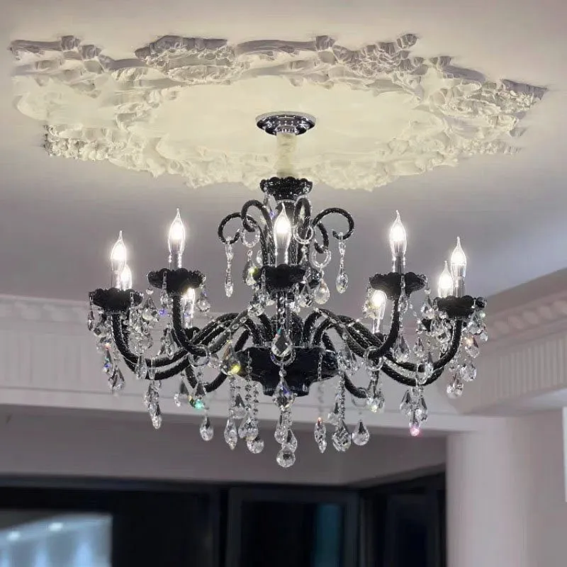 A black crystal chandelier with intricate designs, hanging from a ceiling with ornate plasterwork, in a sophisticated interior space